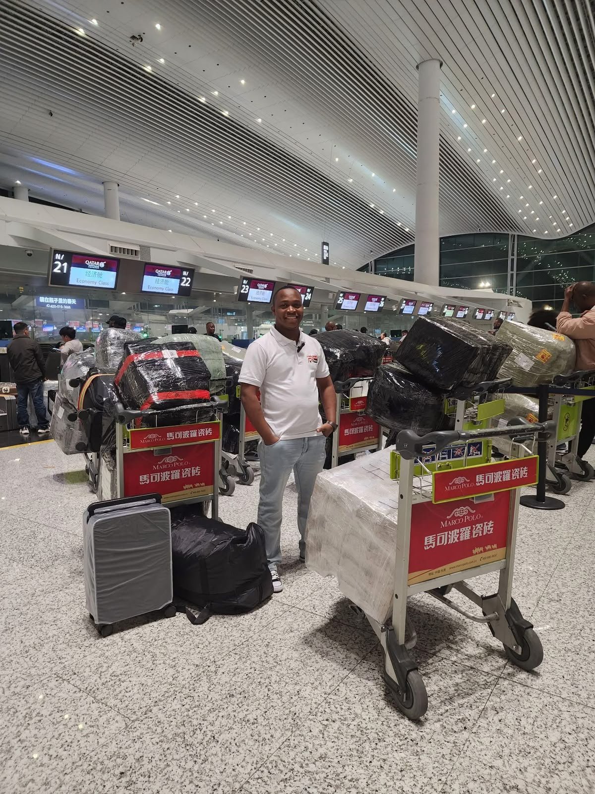 Feliciano num aeroporto na China, ao lado de carrinhos com carga embalada para despachar