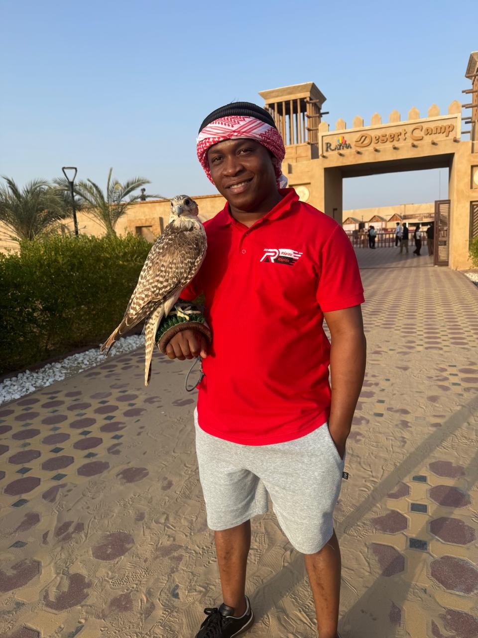 Feliciano com um falcão pousado no braço, de pólo da Rápido Rápido, à entrada de um acampamento no deserto do Dubai